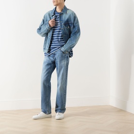 Model wearing Calvin Klein Jeans 90s Mid-Rise Straight Leg Jeans in Andrew blue with denim jacket and striped tee, white trainers.