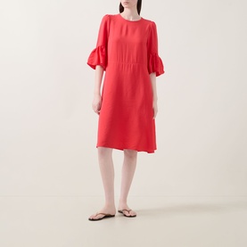 Model wearing InWear Reese Flared Dress in red with round neckline, elbow-length sleeves and flared cuffs, knee-length. Styled with dark flip-flops.