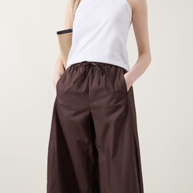 Model wearing InWear Raven Wide-Leg Trousers in dark brown with elasticated drawstring waist, styled with a white sleeveless top.