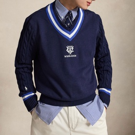 Model wearing Ralph Lauren Wimbledon Logo Hybrid Sweater in Refined Navy with striped V-neck, cable-knit sleeves, styled over a blue striped shirt