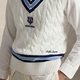 Model wearing Ralph Lauren Wimbledon Logo Cricket Knitted Sweater Vest in cream, cable-knit with navy and blue V-neck stripe trim, over white shirt