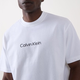 Model wearing Calvin Klein Standard Logo T-Shirt in Bright White with navy chest logo print, crew neck, short sleeves, relaxed fit.