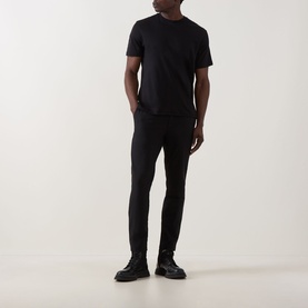 Model wearing Calvin Klein black cotton crew neck T-shirt with slim black trousers and black chunky-sole shoes.