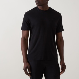 Model wearing Calvin Klein black crew neck T-shirt in slim fit, styled with black trousers. 100% cotton.