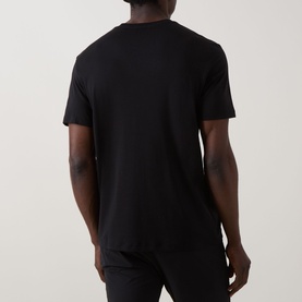 Model wearing Calvin Klein black crew neck T-shirt, back view, 100% cotton, styled with black trousers.