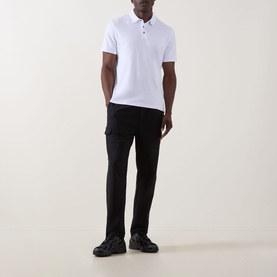 Model wearing Calvin Klein Monogram Logo Polo Shirt in Bright White with black cargo trousers and dark trainers.