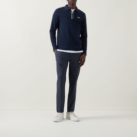 Model wearing Calvin Klein Tech Stretch Slim-Leg Trousers in Dark Sapphire, styled with a navy half-zip sweatshirt and white trainers.