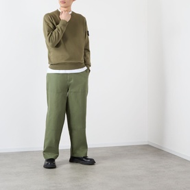 Model wearing Stone Island Verde Militare cotton sweatshirt with matching wide-leg trousers and black loafers.