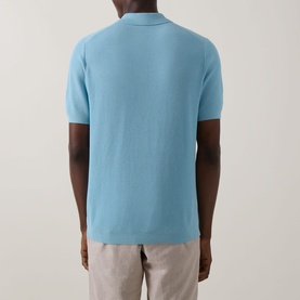 Model wearing Bugatti Structure Polo Shirt in aqua, rear view, showing short sleeves and straight hemline, styled with light beige trousers.