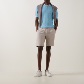 Model wearing Bugatti Structure Polo Shirt in aqua with grey vest overlay, styled with stone shorts and white trainers.