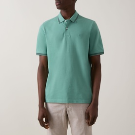 Model wearing Bugatti Double Tipped Logo Polo Shirt in mint, with contrast tipped collar and cuffs, paired with light linen trousers.
