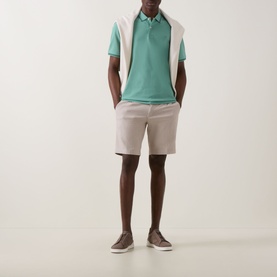 Model wearing Bugatti Double Tipped Logo Polo Shirt in mint with white panels, styled with stone chino shorts and grey trainers.