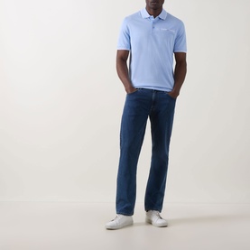 Model wearing Bugatti Contrast Tipped Polo Shirt in light blue with dark navy jeans and white trainers.