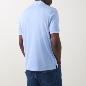 Model wearing Bugatti Contrast Tipped Polo Shirt in light blue, rear view showing straight hem and side split detail, styled with blue jeans.