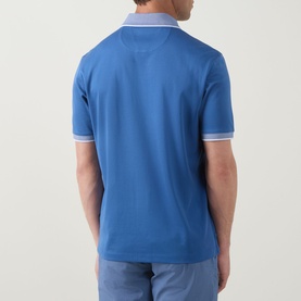 Model wearing Bugatti Tipped Logo Polo Shirt in dark blue, back view, with white tipped collar and cuffs, styled with light blue jeans.