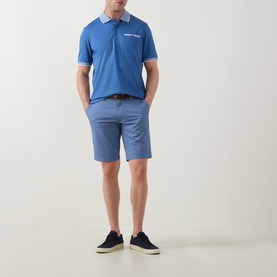 Model wearing Bugatti Tipped Logo Polo Shirt in dark blue with contrast tipped collar, paired with blue shorts and navy trainers.