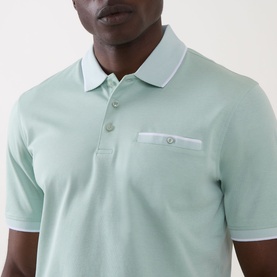 Model wearing Bugatti Patch Pocket Polo Shirt in mint, showing tipped collar, three-button placket and chest patch pocket with button detail.