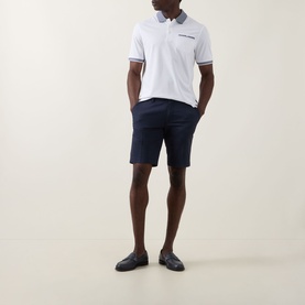 Model wearing Bugatti Twill Slim-Leg Shorts in navy, styled with a white polo shirt and dark loafers.