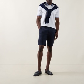 Model wearing Bugatti Twill Slim-Leg Shorts in navy, styled with a white polo shirt and navy sweater draped over shoulders.