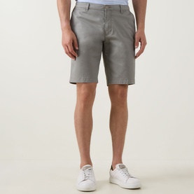 Model wearing Bugatti Classic Bermuda Shorts in light green with belt loops and side pockets, styled with white trainers.