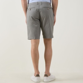 Model wearing Bugatti Classic Bermuda Shorts in light green, rear view showing belt loops and buttoned jet pockets, styled with white trainers.