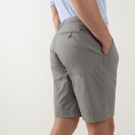 Model wearing Bugatti Classic Bermuda Shorts in light green with rear buttoned jet pocket detail, styled with a striped polo shirt.