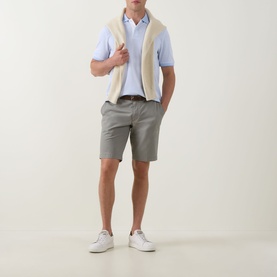 Model wearing Bugatti Classic Bermuda Shorts in light green with cream shearling gilet, light blue polo shirt and white trainers.