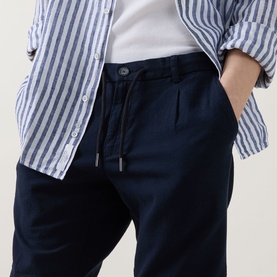 Model wearing Bugatti Lightweight Drawstring Shorts in navy, styled with a blue striped shirt and white tee. Elasticated drawstring waist visible.