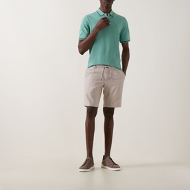 Model wearing Bugatti Lightweight Drawstring Shorts in Stone with elasticated waist, styled with a mint polo shirt and brown trainers.
