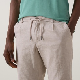 Model wearing Bugatti Lightweight Drawstring Shorts in stone linen-blend, styled with a green T-shirt. Elasticated drawstring waist visible.