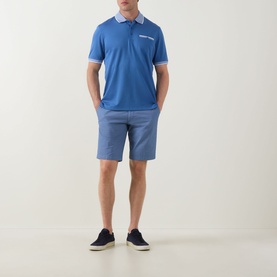 Model wearing Bugatti Summer Bermuda Shorts in light blue with textured finish, styled with a blue polo shirt and navy trainers.