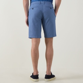 Model wearing Bugatti Summer Bermuda Shorts in light blue with buttoned rear jet pockets, styled with navy canvas shoes.