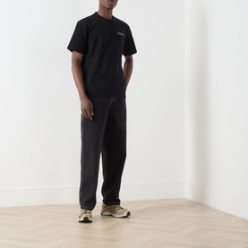 Model wearing Dickies Fairlawn Graphic T-Shirt in black with dark joggers and beige chunky trainers.