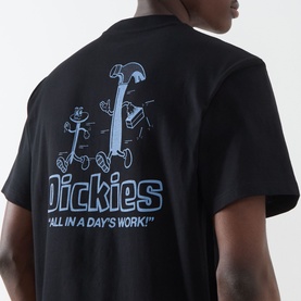 Model wearing Dickies Fairlawn Graphic T-Shirt in black, showing back with "All in a Day's Work" cartoon tool graphic print.