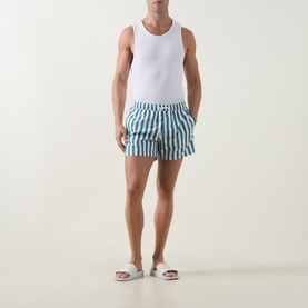 Model wearing Bjorn Borg blue and white stripe swim shorts with white vest top and white slider sandals.