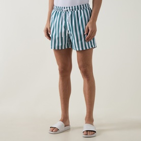 Model wearing Bjorn Borg blue and white vertical stripe swim shorts, styled with white slider sandals.