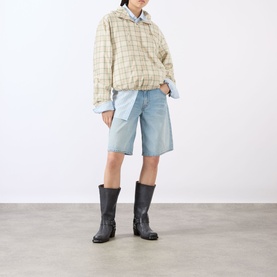 Model wearing Acne green/orange check cotton jacket with light blue denim shorts and dark knee-high boots.