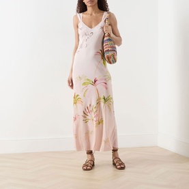 Model wearing Hayley Menzies Palmera Silk Slip Dress in pink with palm print, cutwork detail and scalloped straps, styled with tan sandals and woven