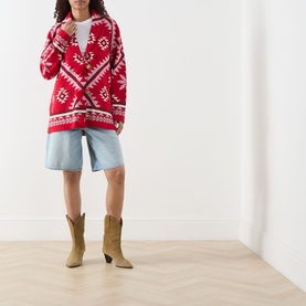Model wearing Hayley Menzies Sundance Printed Cardigan in red with cream tapestry motifs, styled with denim shorts and tan cowboy boots.