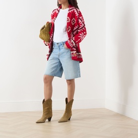 Model wearing Hayley Menzies Sundance Printed Cardigan in red with tapestry motifs, styled with denim shorts, tan cowboy boots, and a woven bag.