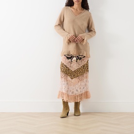Model wearing Hayley Menzies Fringe Cashmere Sweater in camel with V-neckline and fringed trims, styled with a printed midi skirt and khaki boots.