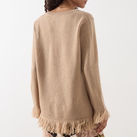 Model wearing Hayley Menzies Fringe Cashmere Sweater in camel, rear view showing fringed hem trim and long sleeves.