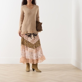 Model wearing Hayley Menzies Fringe Cashmere Sweater in camel with V-neckline and fringed hem, styled with printed midi skirt and tan boots.