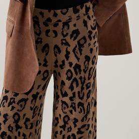 Model wearing Hayley Menzies Cosmic Cat trousers in brown leopard-print knit, styled with a tan suede jacket.