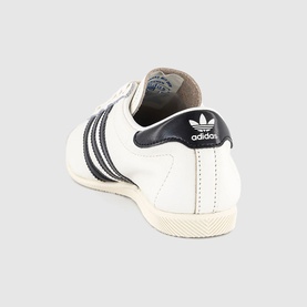 Adidas trainer in core white and core black, leather upper with three stripe detail, cream rubber sole, heel tab view