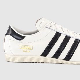 Adidas Paris trainer in core white with black three stripes, gold branding detail, and cream rubber cupsole