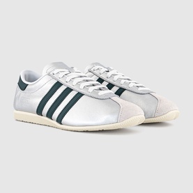Adidas silver metallic trainers with dark green three-stripe detail, suede heel panel, and cream rubber sole