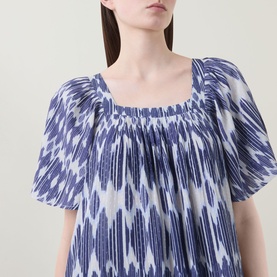 Model wearing Masai blue ikat-print dress with square neckline, shirred bodice and short puff sleeves