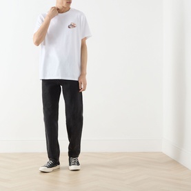 Model wearing Levi's You've Been Served Graphic T-Shirt in white with small chest graphic, styled with black trousers and black canvas trainers.