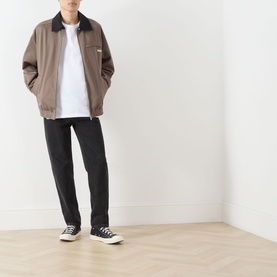 Model wearing Levi's You've Been Served Graphic T-Shirt in white, styled with a brown harrington jacket, black trousers and black trainers.